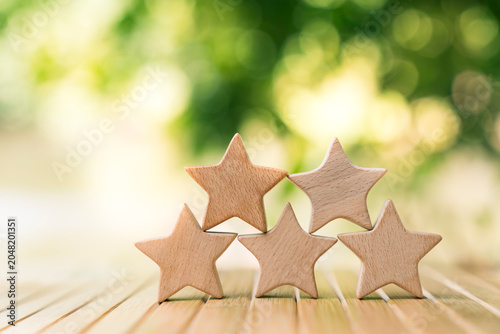 Cuadro en lienzo Five wooden star shape models on table with green nature bokeh background