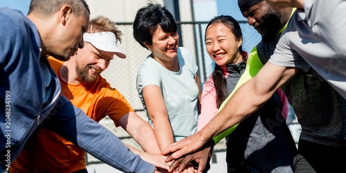 Fotografía Diverse group of people joining hands outdoors in a team spirit gesture