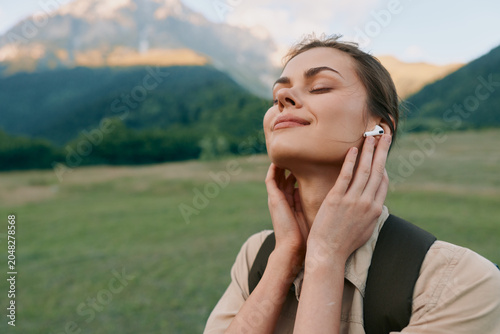 Photos A woman enjoys nature outdoors with a calm, uplifted expression, listening to music