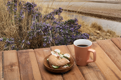 Принти на полотні Sesame bagel sandwich with cucumber and cream cheese, wooden plate and ceramic m