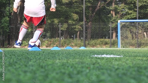 사람 축구 선수 스포츠 훈련 코트 야외 일상 소품 디테일 자재: 야외 인조잔디구장에서 유소년 축구 선수가 발바닥으로 공을 밟으며 컨트롤하는 하체 중심의 로우앵글 동영상 클립입니다.