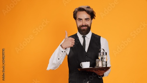 Fotografie Accomplished valet gives thumbs up in studio, displays agreement sign and is enthusiastic on camera