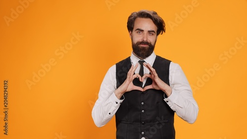 Tableau sur toile Butler indicates heart shaped sign in studio, working at five star restaurant and expressing honest emotions