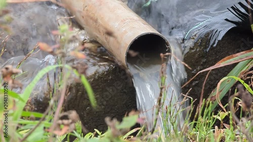 4K slow‑motion zoom close‑up of muddy rainwater overflowing from a rice‑field drainage pipe in Japan