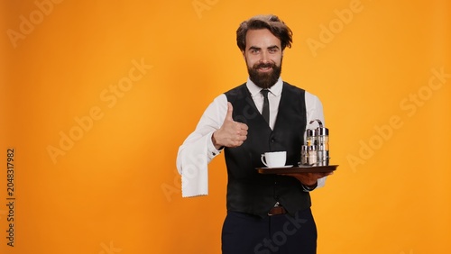 Konstfotografi Anccomplished valet raises thumbs up in studio, displays agreement emblem, is enthusiastic on camera