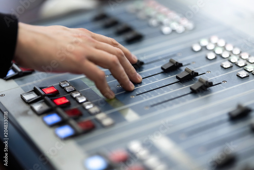 Obraz na plátne A person's hand adjusts the faders and presses buttons on a professional audio m