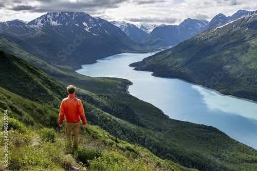 Mountaineer enjoys views of blue lake and mountains on Twin Peaks Trail, Eklutna Lake, Chugach Mountains, Chugach State Park, Alaska, USA