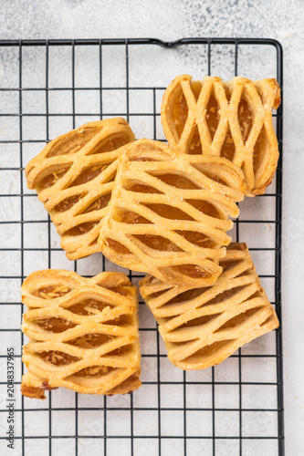 Bild auf Leinwand Homemade apple pastries with flaky puff dough and fruit filling on metal rack