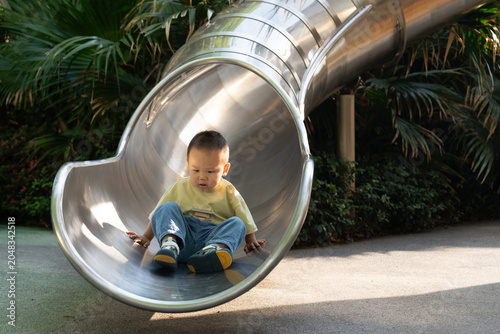 Toddler boy resting at bottom of metal slide