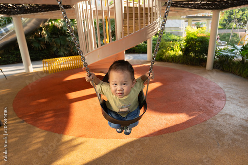 Little boy enjoying swing ride in sunny park