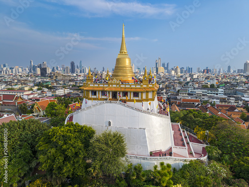 Bangkok, Thailand - 26 April 2026: Aerial view of Wat Saket Ratchawora Mahawihan, the Golden Mount, with its golden chedi rising above the city skyline under a clear blue sky.