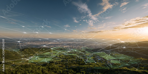 A scenic aerial view captures a sprawling city nestled amidst verdant hills and valleys under a vast, cloud-strewn sky at sunset
