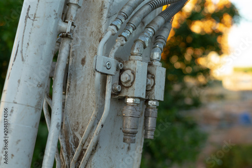 Detailed close-up of weathered metal hardware and insulated electrical cables mounted on a utility pole, with an outdoor background softly blurred by warm