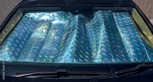 Sun protection with an embossed, shimmering metallic foil behind the windshield of a motor vehicle.