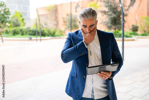 Bilde på lerret Businessman feeling concerned looking at tablet outdoor