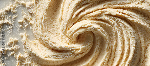 Close-up of a swirl of creamy, off-white, textured substance, creating a circular pattern. Soft lighting enhances details