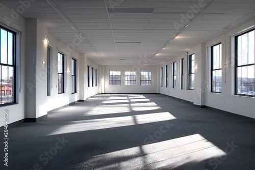 An expansive, empty room bathed in sunlight. Large windows provide city views; neutral colors create a bright, spacious atmosphere