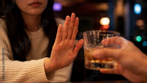 Woman refusing alcohol offered hand gesture in bar setting
