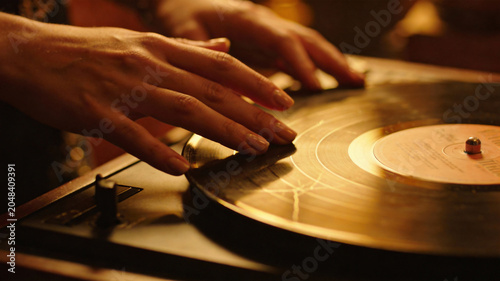 Close-up of hands playing a vintage vinyl record on a turntable, capturing analog music culture, nostalgia, and the timeless charm of classic audio.