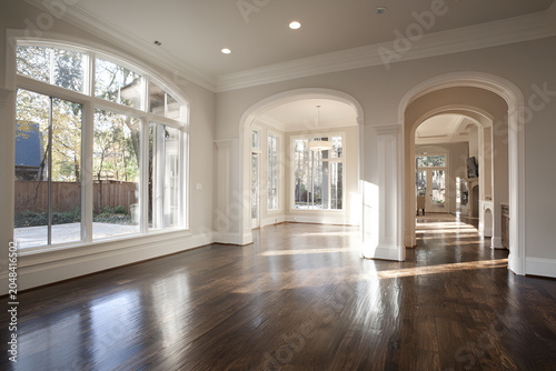 Expansive interior showcasing hardwood floors, arched doorways, large windows, and an airy, sunlit ambiance