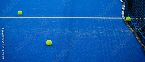 Fotografia Balles de tennis dispersées sur une piste de padel bleu, format bannière