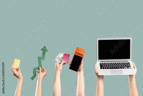 Female hands with credit cards, arrow, payment terminal and laptop on green b...