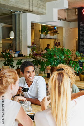 Man  smile and friends in cafe with coffee  social gathering and bonding together on weekend break. Happy  person and group hangout in restaurant with beverage  hospitality and listening to gossip.