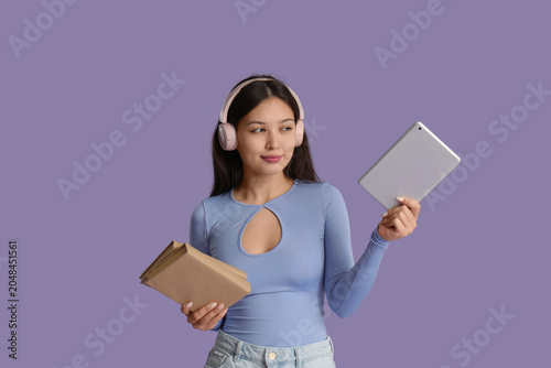 Beautiful young Asian woman in headphones listening to audiobook with modern ...