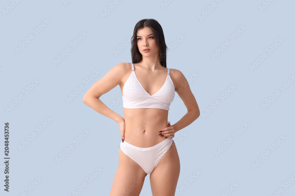 Obraz premium Pretty young woman in white underwear on blue background