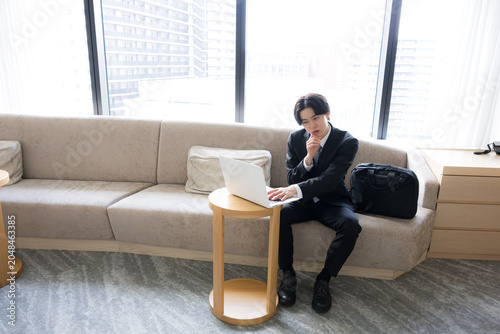 Bilde på lerret A young businessman using his laptop to attend online meetings at a hotel during