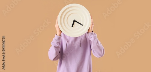 Woman with clock on beige b...
