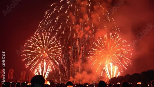 Brilliant gold and orange fireworks exploding in the night sky above a city