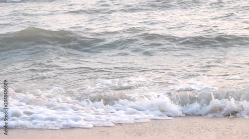 Detailed shot of white foamy sea waves washing over a clean sandy shore, perfect for nature and relaxation backgrounds.