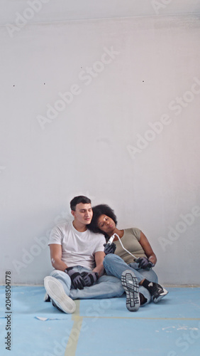 Foto Two individuals rest on a blue floor in a minimalist room