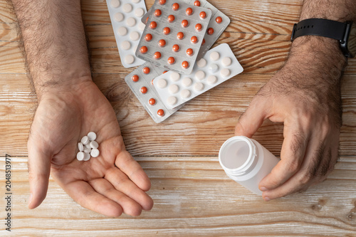Pills in hand top view, taking painkillers, white medical tablets
