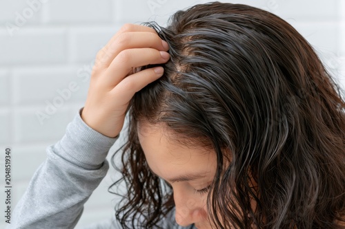 Woman touching oily dark hair and scalp