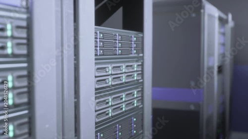 Tight view of server drive bays stacked drives with green status lights, metallic front panels, ventilation holes, polished rack rails, ambient cool tone