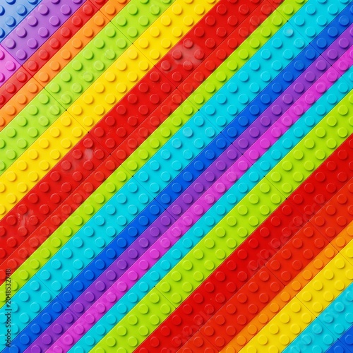 A vibrant, top-down macro view of colorful toy building bricks arranged in crisp, diagonal rainbow stripes for a playful, textured geometric background.