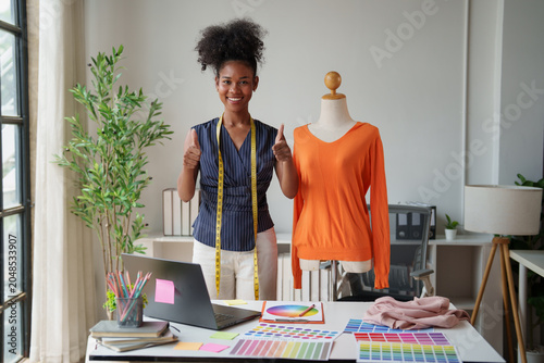 Fotografía African American fashion designer standing by her workspace, giving thumbs up, e