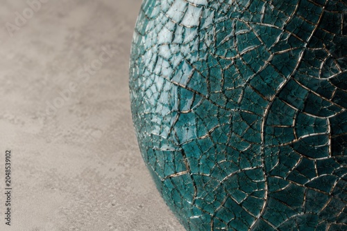 Macro Close-up of Teal Crackle Glaze Ceramic Surface with Intricate Web Patterns and Minimalist Warm-Grey Stone Background