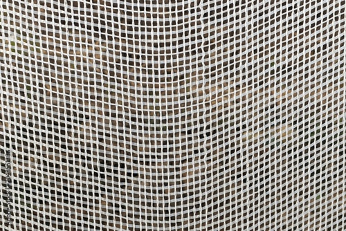 Full frame of white plastic woven mesh safety netting pattern texture.