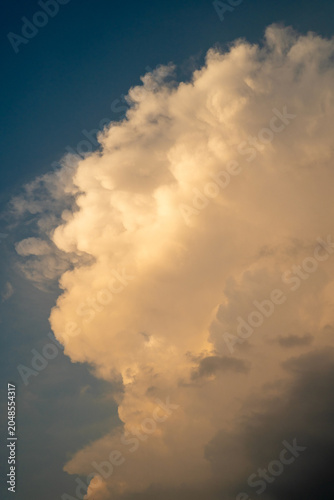 A majestic cumulus cloud against a blue sky at dusk.