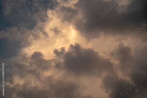 Dramatic cloudscape with golden light peeking through dark storm clouds.