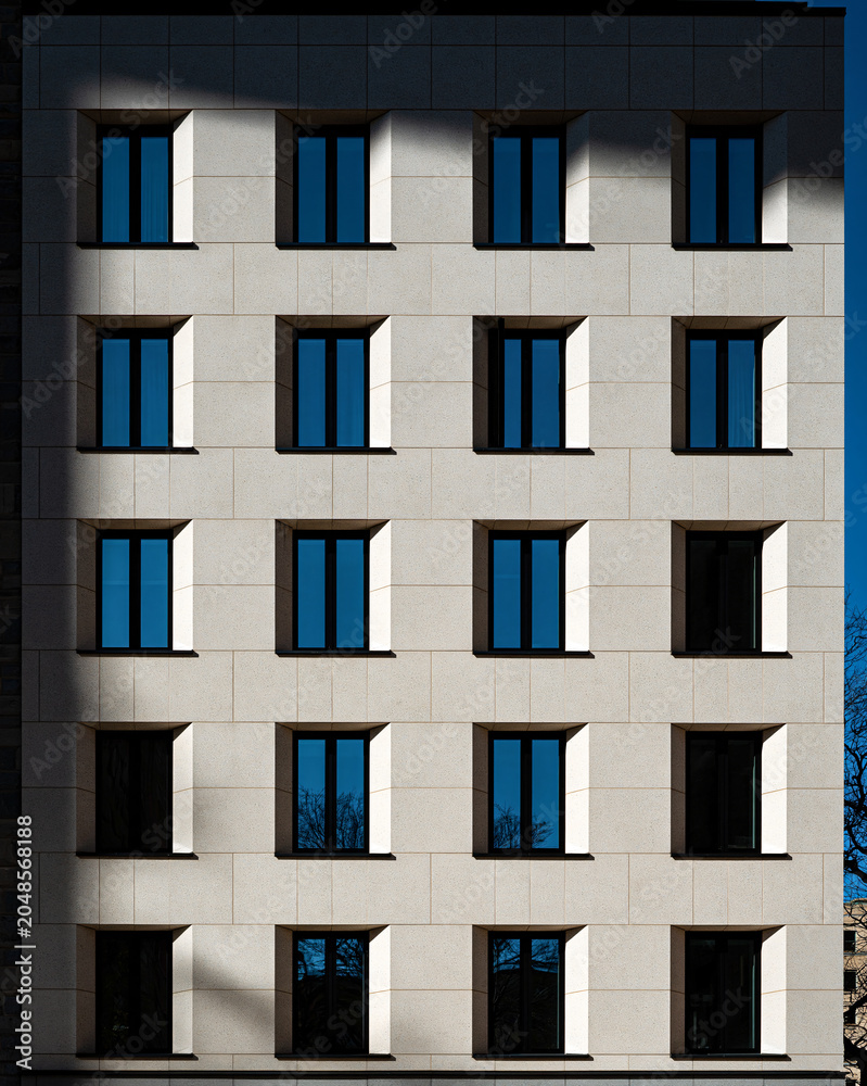 Obraz premium Modern Facade with Geometric Windows A stark, contemporary building facade showcases a repeating pattern of identical windows.