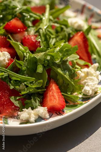 Fresh summer salad with strawberries watermelon greens and cheese served on decorative plate