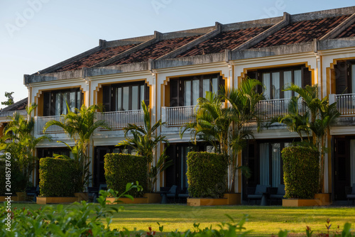 Fotografía Two Story Yellow Resort Terraces with Palm Trees and Lawn