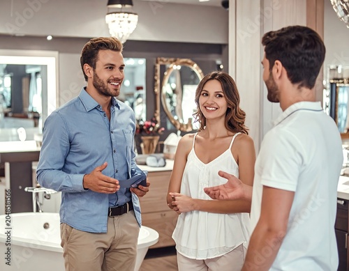 A man and woman discuss with a salesman in a bathroom showroom