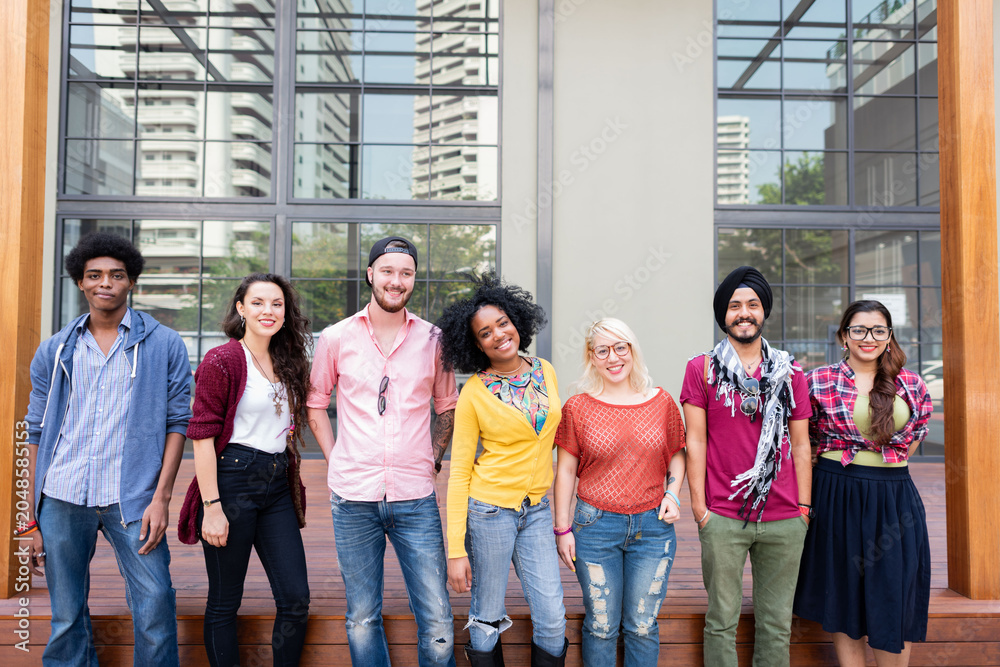 Obraz premium Group of diverse young adults smiling outside a modern building.