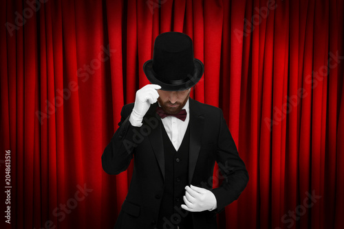 Obraz na płótnie Magician performing on stage with red curtains