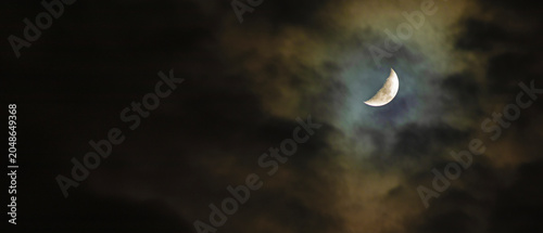 Partial moon in the sky glowing through thick clouds